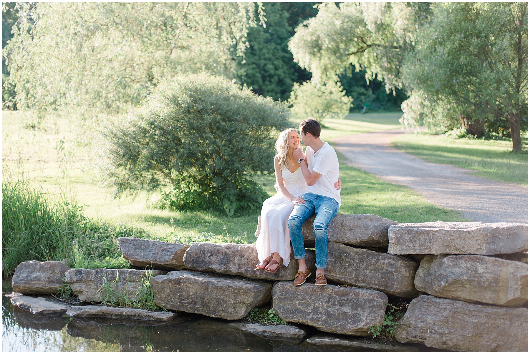couple sitting on rocks by river at dominion arboretum