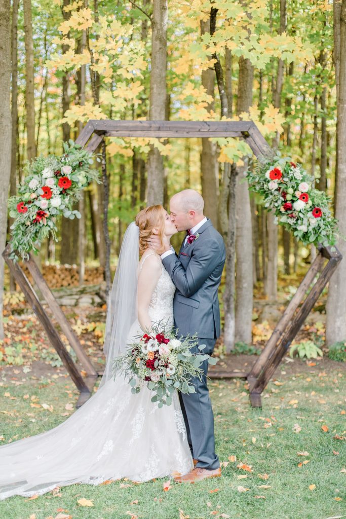 bride and groom having first kiss at the altar of their petite backyard wedding