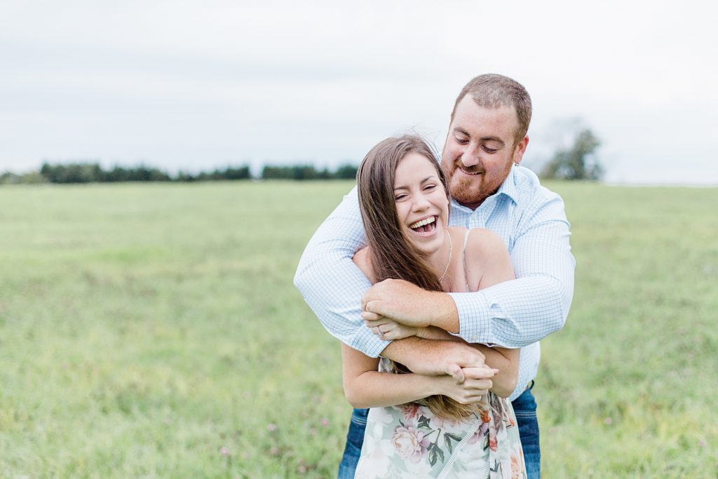 couple wrapped up in a big hug laughing in the field at pinheys point