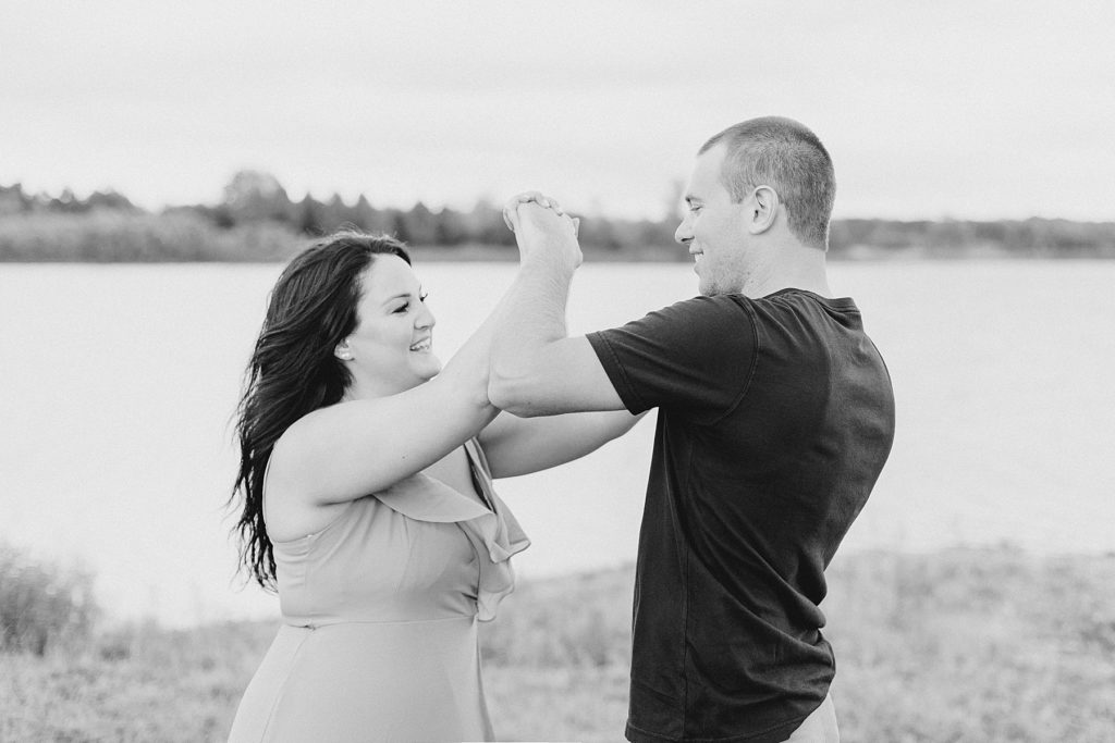 couple play fighting by the lake all dressed up for their engagement session