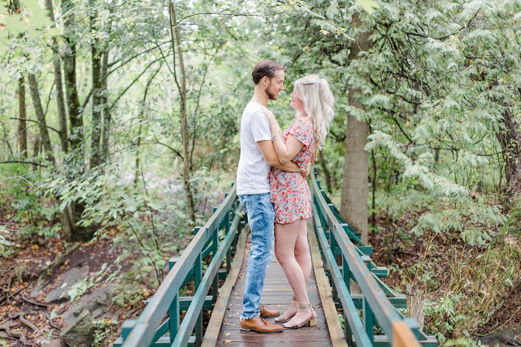 couple standing looking at eachother on a cute bridge