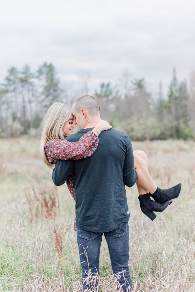 guy carrying girl in the middle of the field on a fall day during couples session