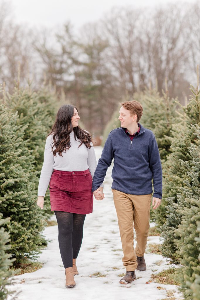 couple walking in rows of christmas trees