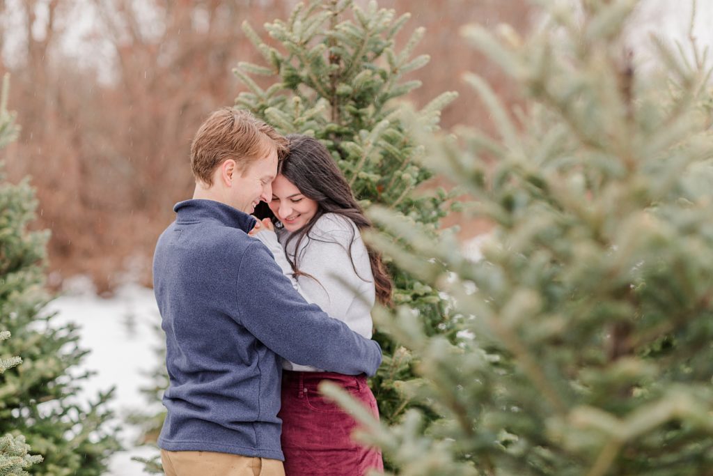 couple cuddling to keep warm at the christmas tree farm