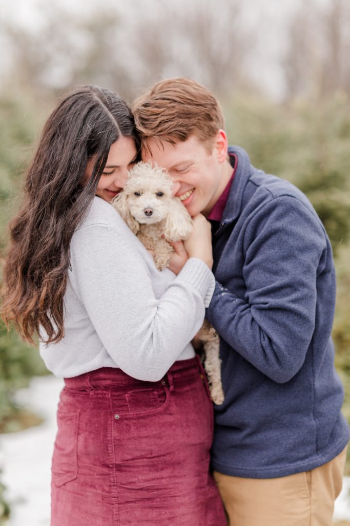 couple cuddling their puppy at the christmas tree farm