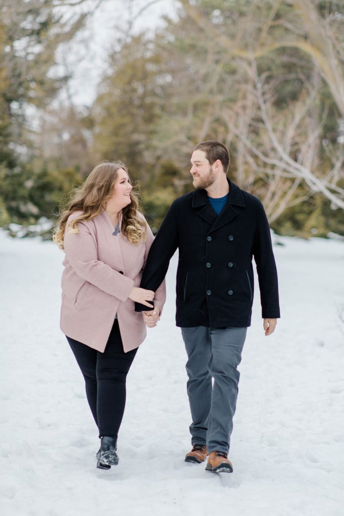 couple walking towards camera at winter engagement session holding hands