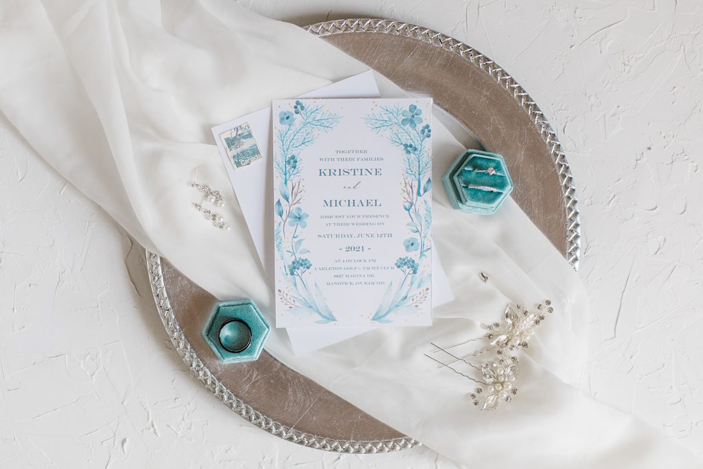 wedding details photo for carleton golf and yacht club wedding. Photo of invitation suite with rings inside a velvet ring box and earings and hair pieces gently lay on a sheer piece of white material 