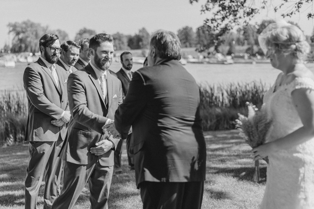 groom shaking father of the bride's hand at the beginning of the ceremony at the carleton golf and yacht club wedding