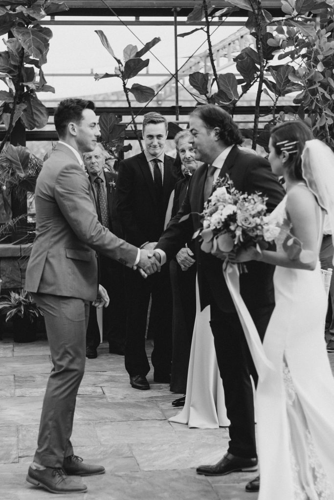 Groom shaking bride's father's hand at the beginning of the ceremony during Aquatopia Wedding photographed by Brittany Navin Photography