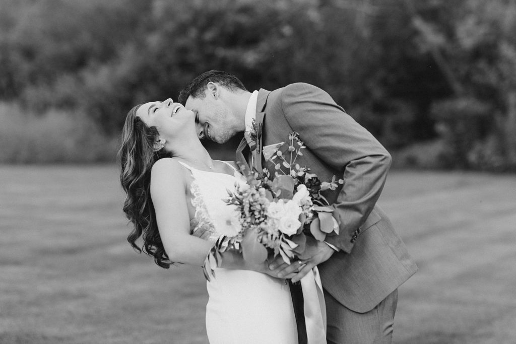 groom kissing her neck at Aquatopia wedding photographed by Brittany Navin Photography