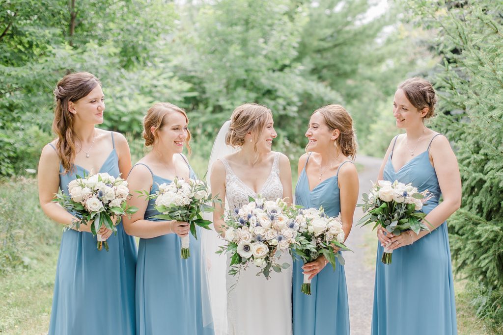 bridesmaids laughing with the bride wearing dusty blue dresses at Ottawa wedding