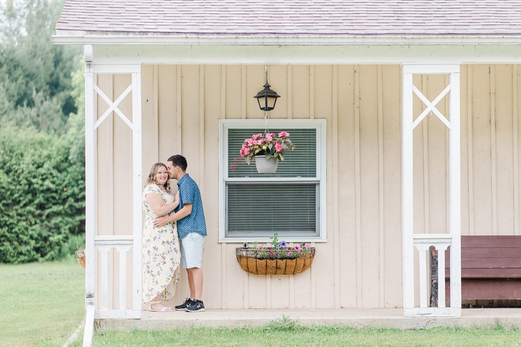 couple cuddled up under the porch rainy summer Mill of Kintail Engagement session with Brittany Navin Photography in Almonte, ON