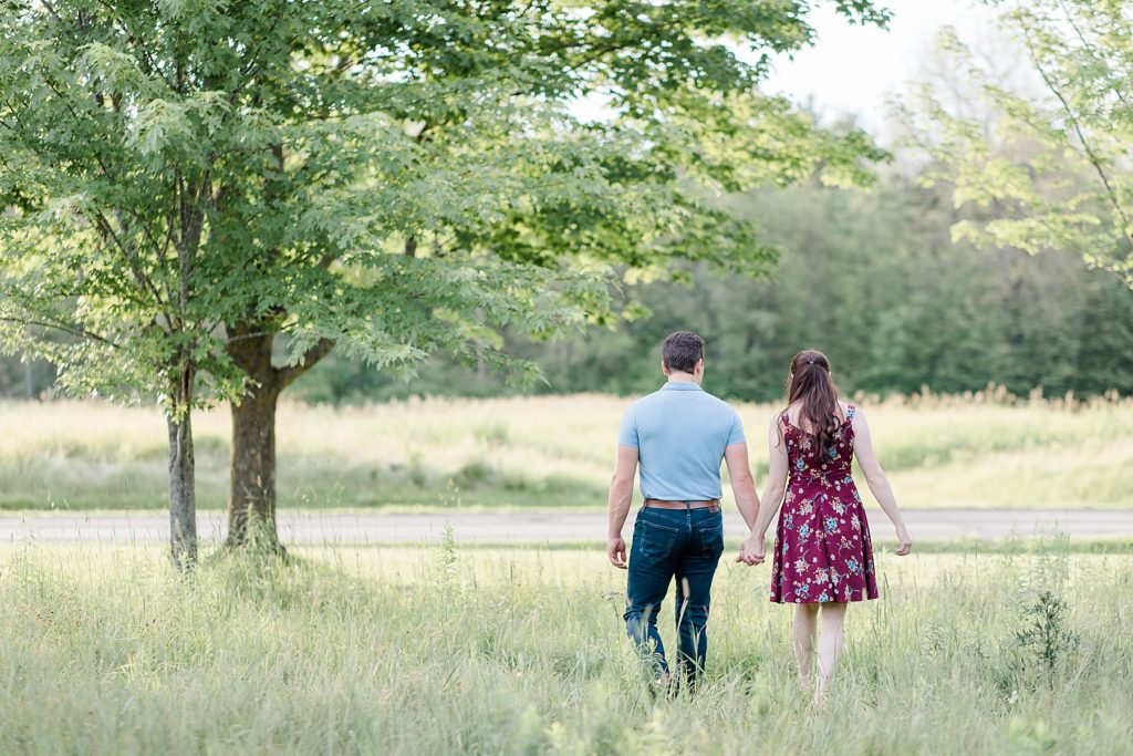 couple walking away in the field at their engagement in Almonte, ON, at the Mill of Kintail with Brittany Navin Photography