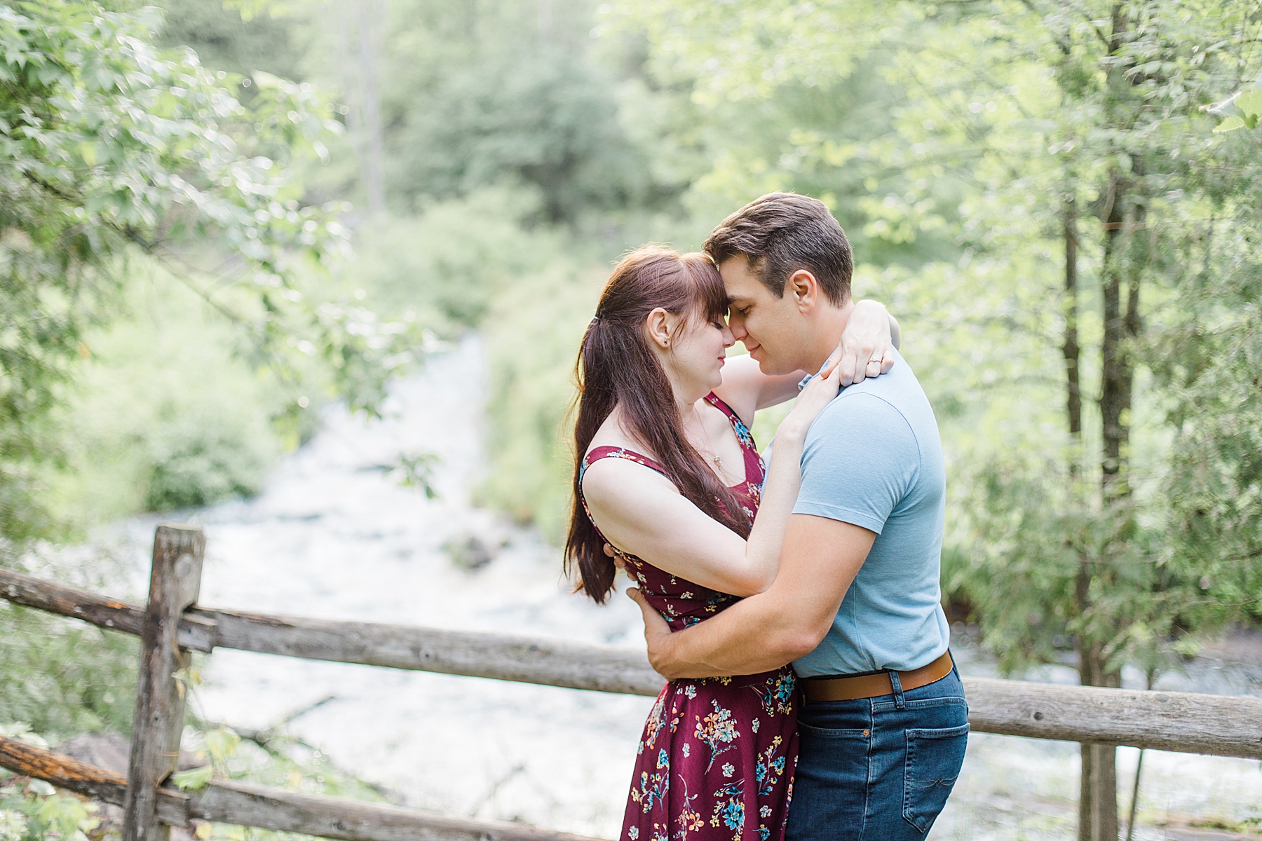 couple forehead to forehead by the water at engagement in Almonte, ON, at the Mill of Kintail with Brittany Navin Photography
