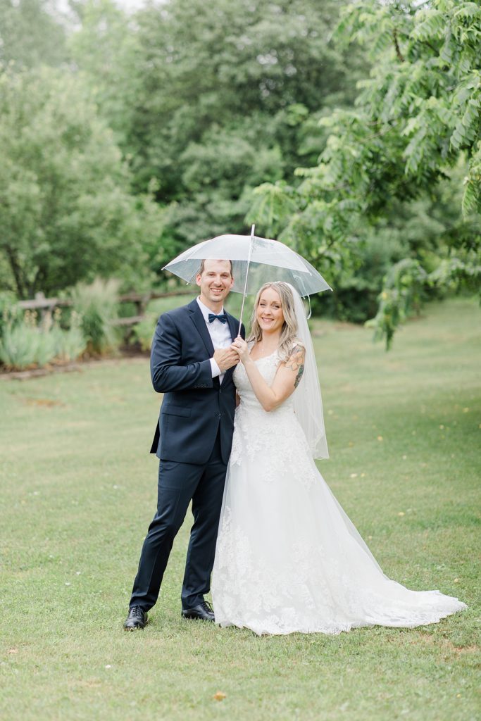 bride and groom classic portrait with a clear umbrella on rainy day at Wedding with Brittany Navin Photography in Almonte, Ontario