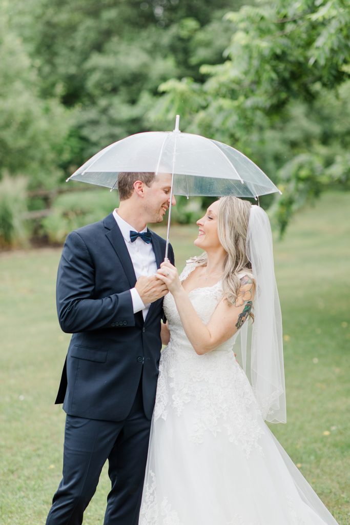 bride and groom sharing a clear umbrella in the rain at Wedding with Brittany Navin Photography in Almonte, Ontario