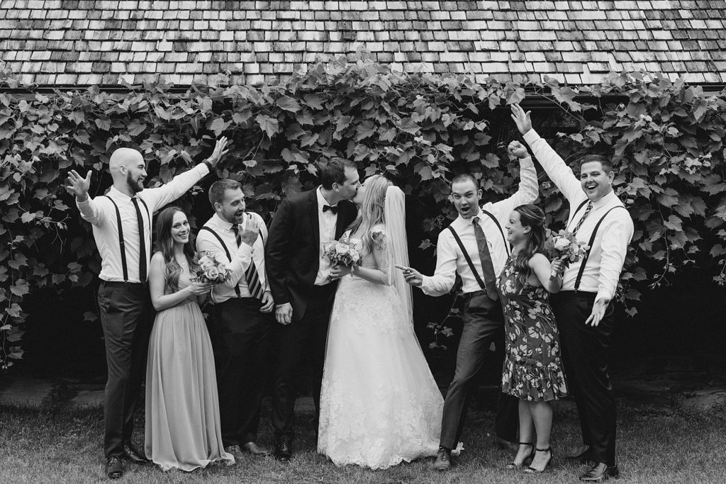 Bride and groom kissing while their bridal party is cheering at Mill of Kintail Wedding with Brittany Navin Photography in Almonte, Ontario