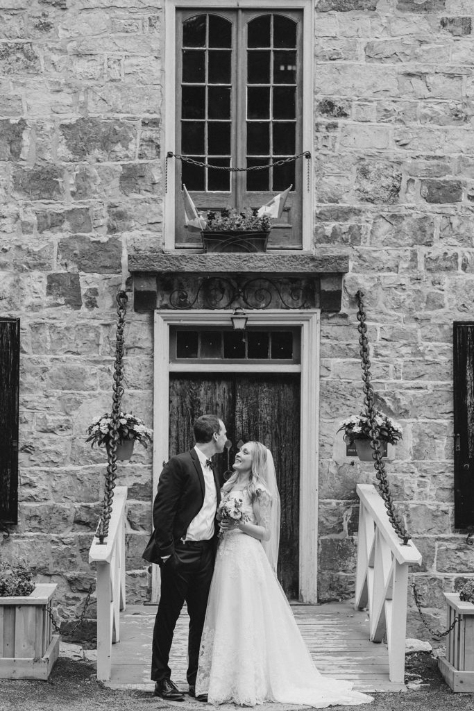 bride and groom in front of stone building at Mill of Kintail Wedding with Brittany Navin Photography in Almonte, Ontario