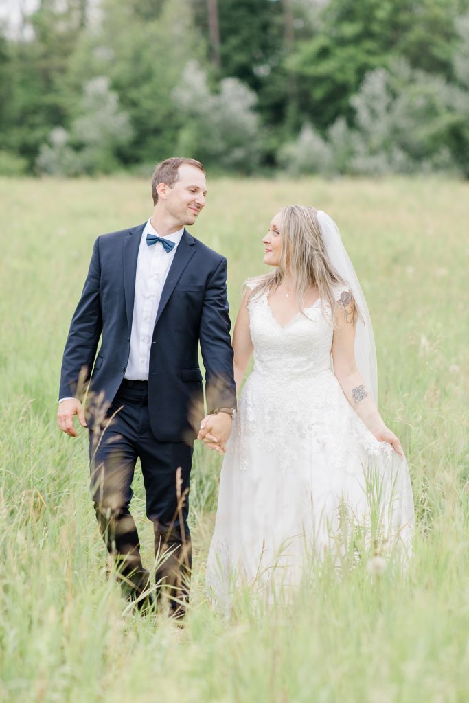 bride and groom walking through field at Mill of Kintail Wedding with Brittany Navin Photography in Almonte, Ontario
