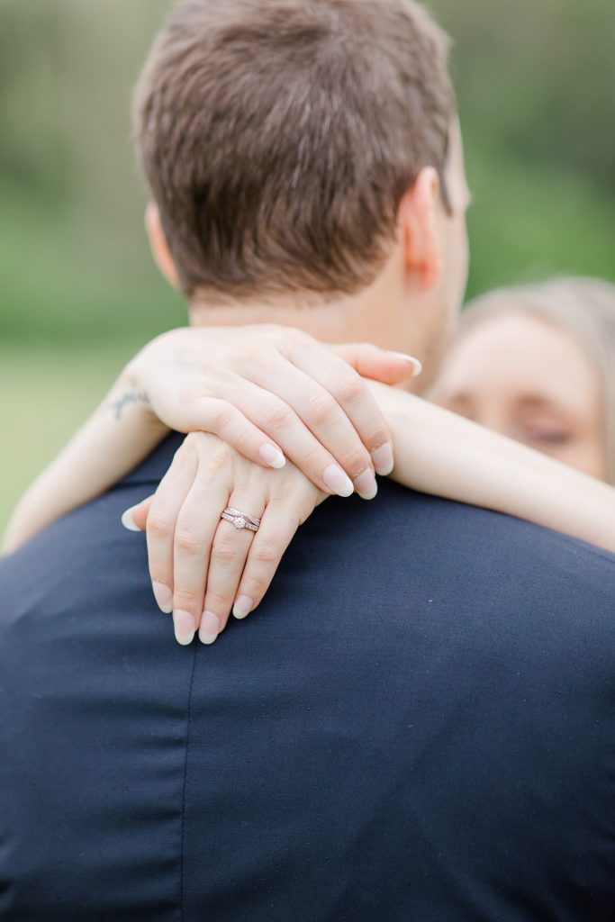 close up photo of brides engagement ring and wedding band as her arms are draped around his neck at Mill of Kintail Wedding with Brittany Navin Photography in Almonte, Ontario