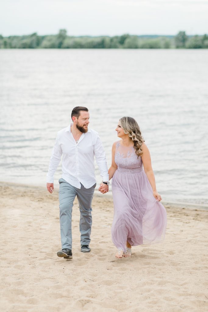 fiances holding hands during their engagement session at petrie island beach