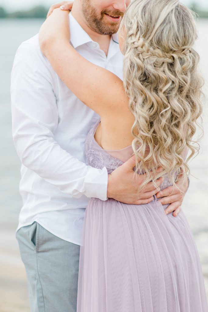 groom to be has arms wrapped around his bride to be during their ottawa beach engagement session