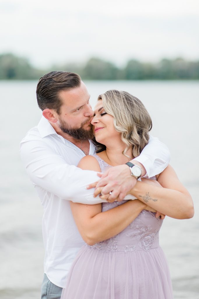 he has her all wrapped up in his arms during Petrie Island Beach Engagement session