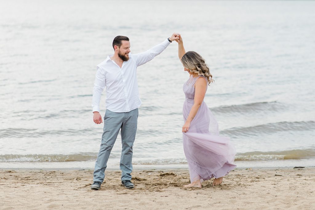 bride to be being twirled around by her fiance during petire island beach engagement session