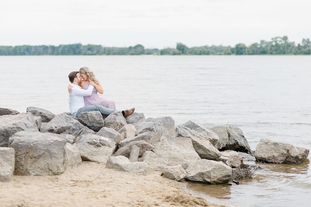 finaces sitting together on boulder sized rocks during their ottawa beach engagement session