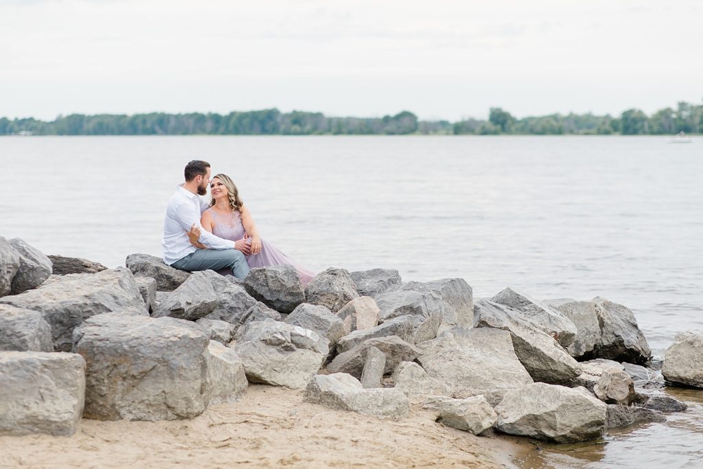 finace's sitting on the rocks at their Petrie Island Beach Engagement session