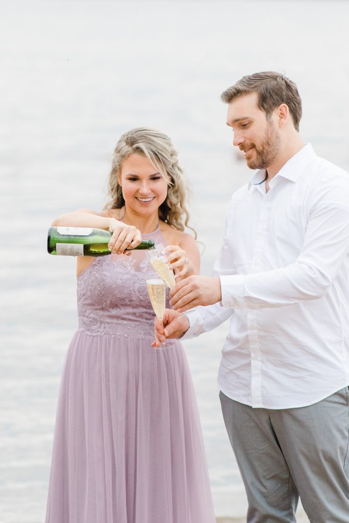 fiance pouring a champagne drink for him during their ottawa beach engagement session