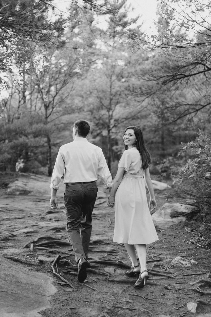 Couple walking through forest at Eagle's Nest Engagement in Calabogie, Ontario with Brittany Navin Photography
