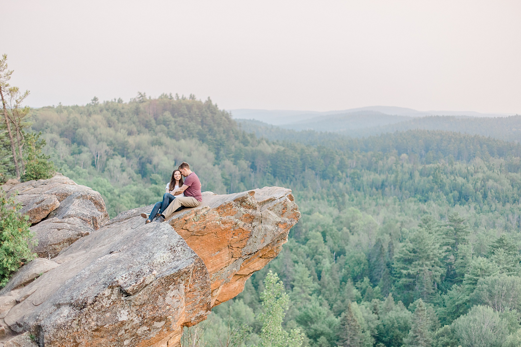 couple sitting together on rocky cliff at Eagle's Nest Lookout Engagement in Calabogie, Ontario with Brittany Navin Photography