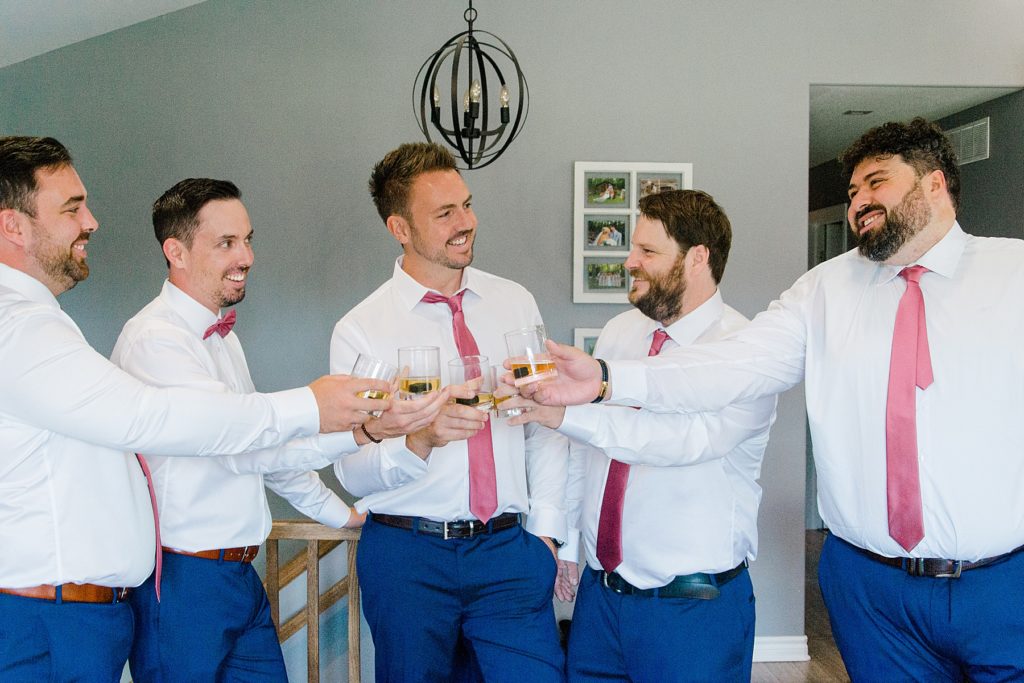 groom and groomsmen cheersing their drinks during groom prep