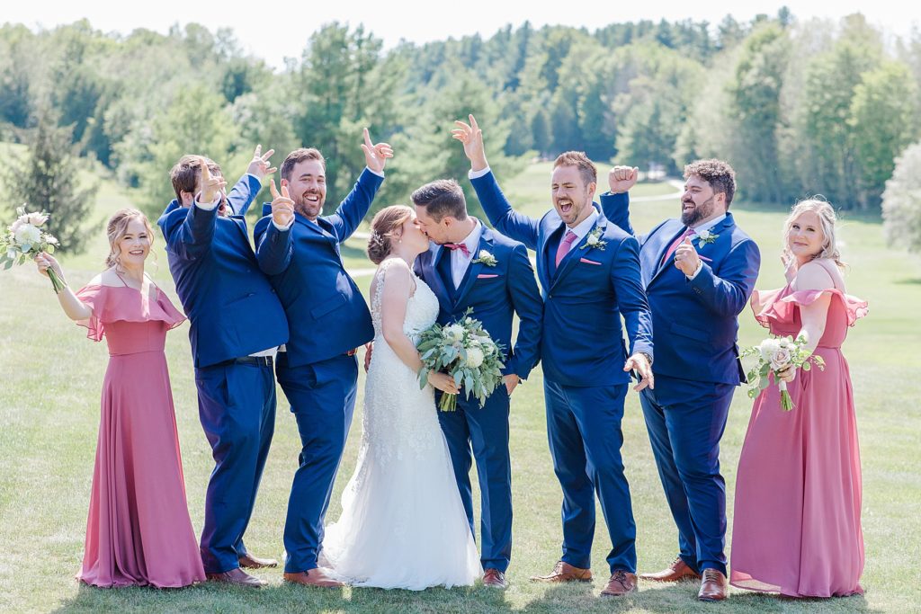 wedding party cheering as bride and groom kiss at timber run golf course wedding in Lanark, Ontario photographed by Brittany Navin