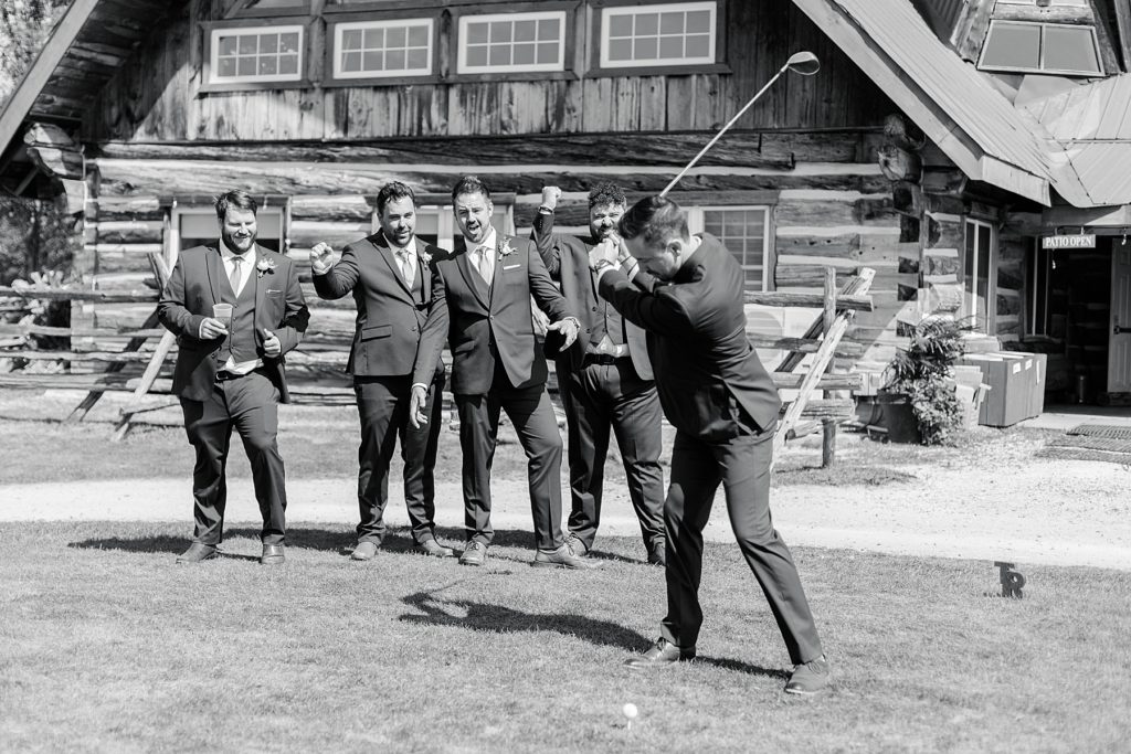 Groom is golfing while his groomsmen cheer him on at timber run golf course wedding in Lanark, Ontario photographed by Brittany Navin