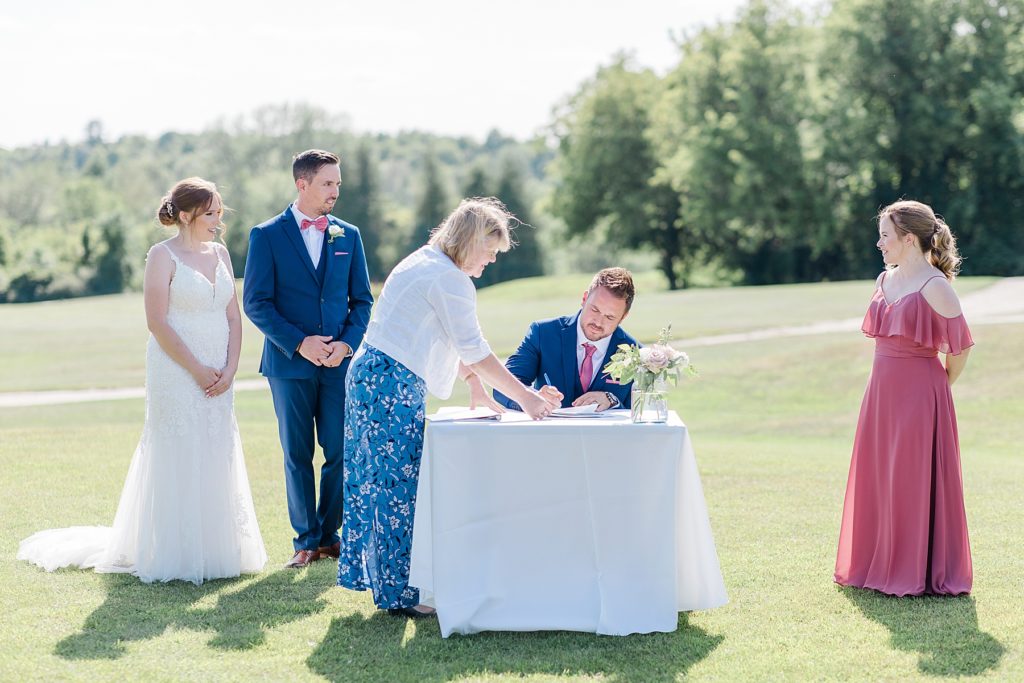 groomsmen signing wedding papers at timber run golf course wedding in Lanark, Ontario photographed by Brittany Navin
