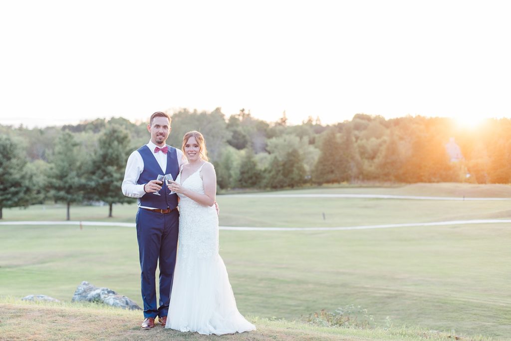 bride and groom holding champagne glasses during sunset at timber run golf course wedding in Lanark, Ontario photographed by Brittany Navin