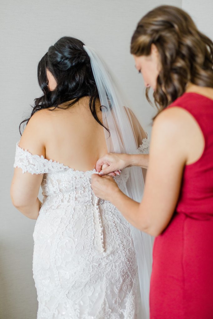 brides mom is doing up brides dress at Adelina Barn Wedding Photographed By Brittany Navin Photography