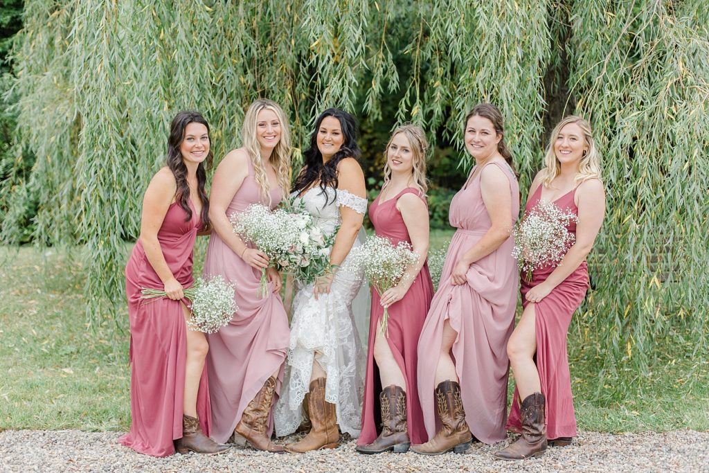 bride and bridal party showing off their cowgirl boots at Adelina Barn Wedding Photographed By Brittany Navin Photography
