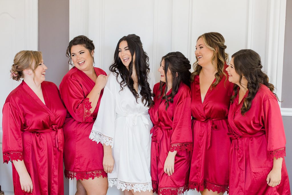 bride and bridemaids in matching red robes laughing together in bridal suite at Grand Hotel in Carleton Place Photographed by Brittany Navin Photography