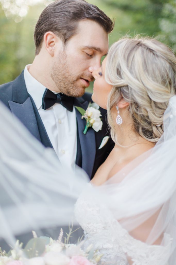 bride and groom portrait with veil in foreground at bean town ranch double wedding photographed by Brittany Navin Photography