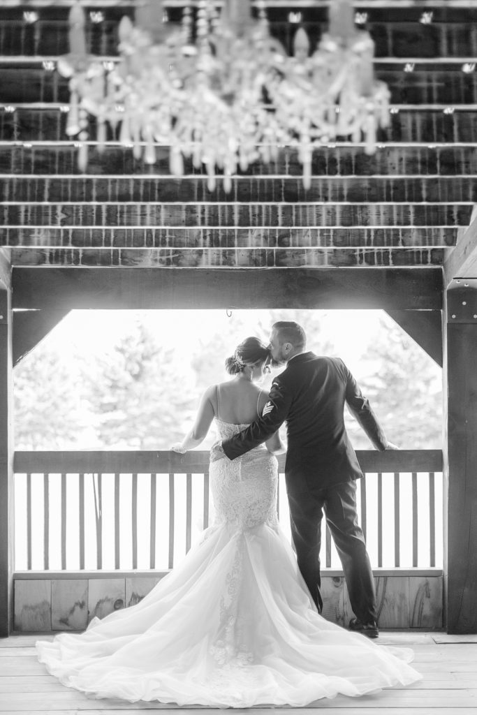 bride and groom at balcony under chandelier at bean town ranch double wedding photographed by Brittany Navin Photography