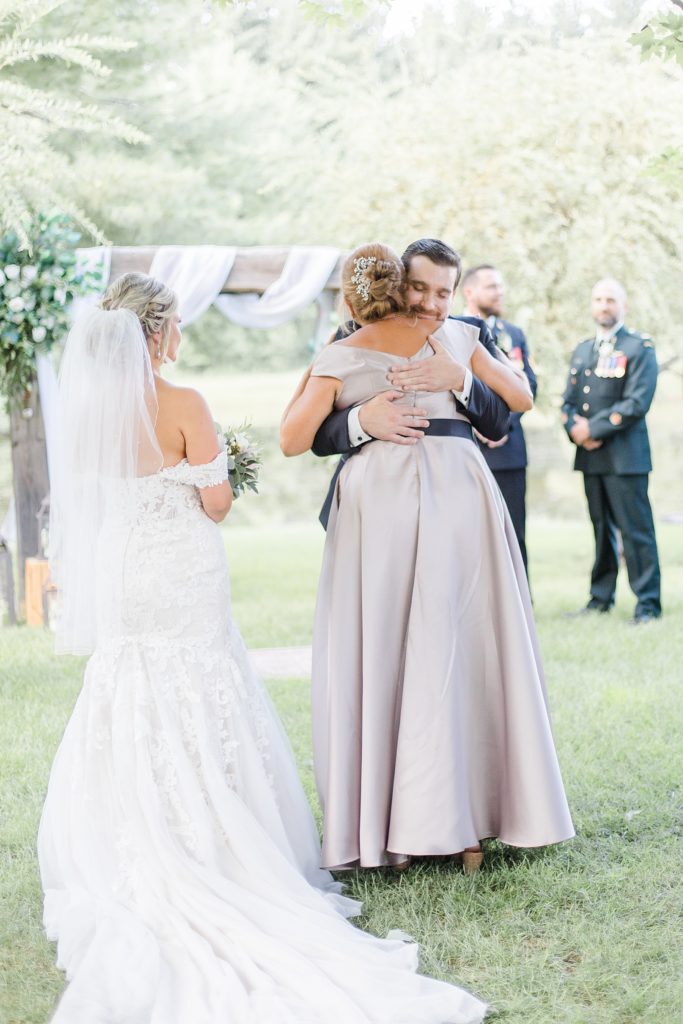mother of bride hugging grooma fter walking bride down the aisle at bean town ranch double wedding photographed by Brittany Navin Photography