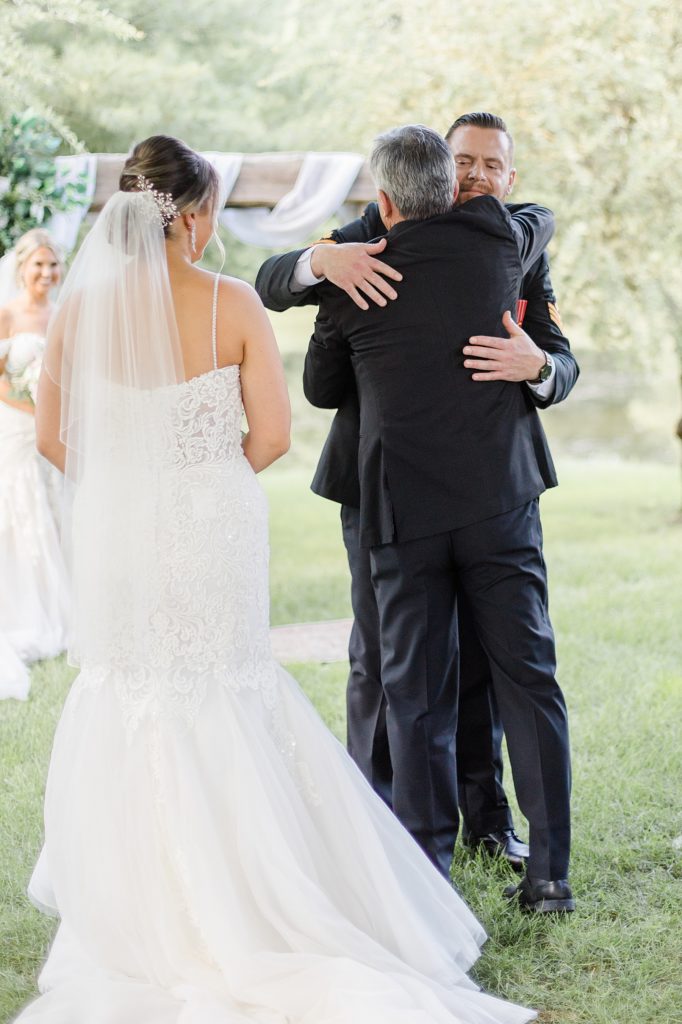 father of the bride hugging groom after walking her down the aisle at bean town ranch double wedding photographed by Brittany Navin Photography