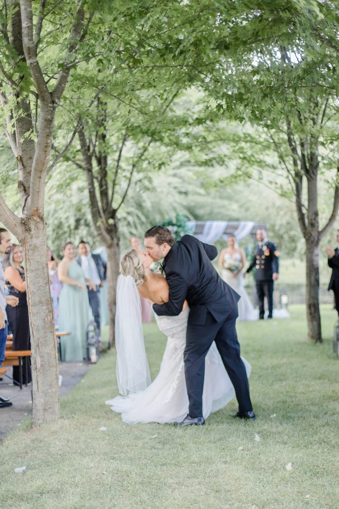 groom kisses bride halfway down the aisle after being married at bean town ranch double wedding photographed by Brittany Navin Photography