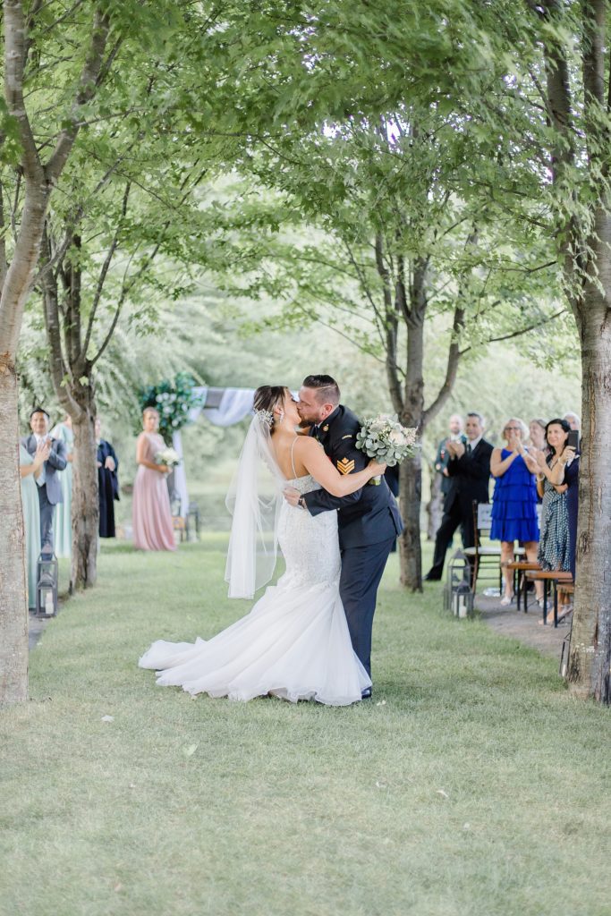 groom kisses bride half way down the aisle after being married at bean town ranch double wedding photographed by Brittany Navin Photography