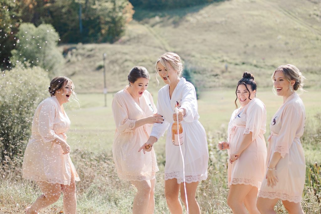 bride and bridesmaids pop champagne at Calabogie Peaks wedding photographed by Brittany Navin Photography