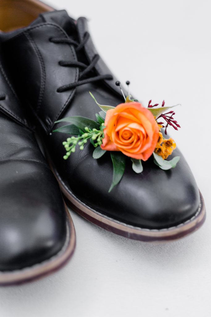 close up of boutonniere with grooms shoes for a grooms detail photo at Calabogie Peaks wedding photographed by Brittany Navin Photography