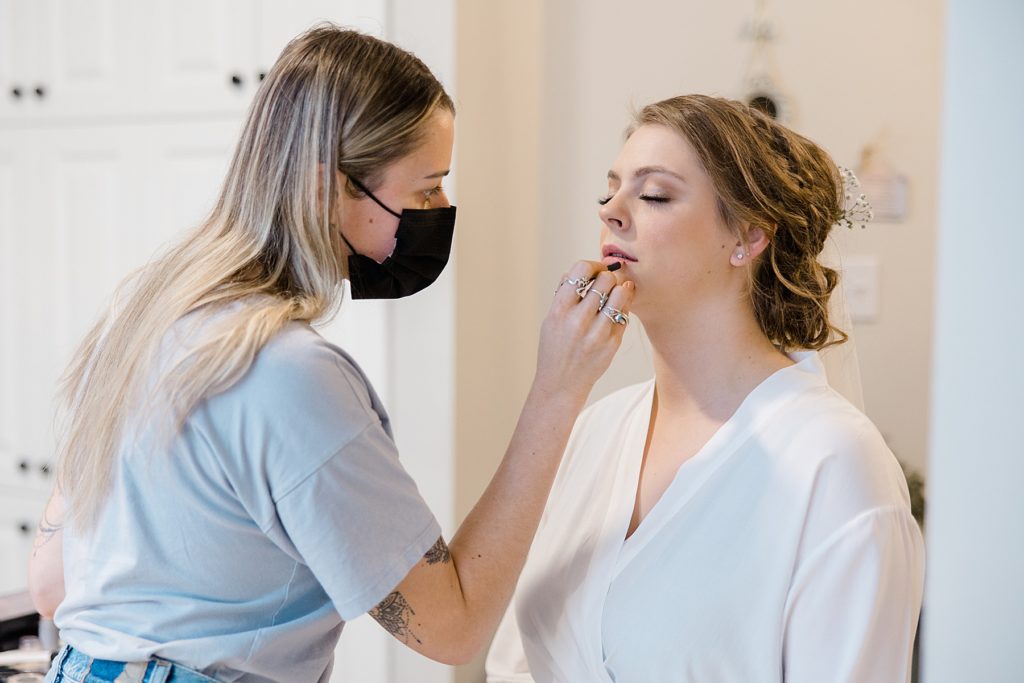 Bride getting makeup done at getting ready location for for temples country winter wedding photographed by Brittany Navin Photography